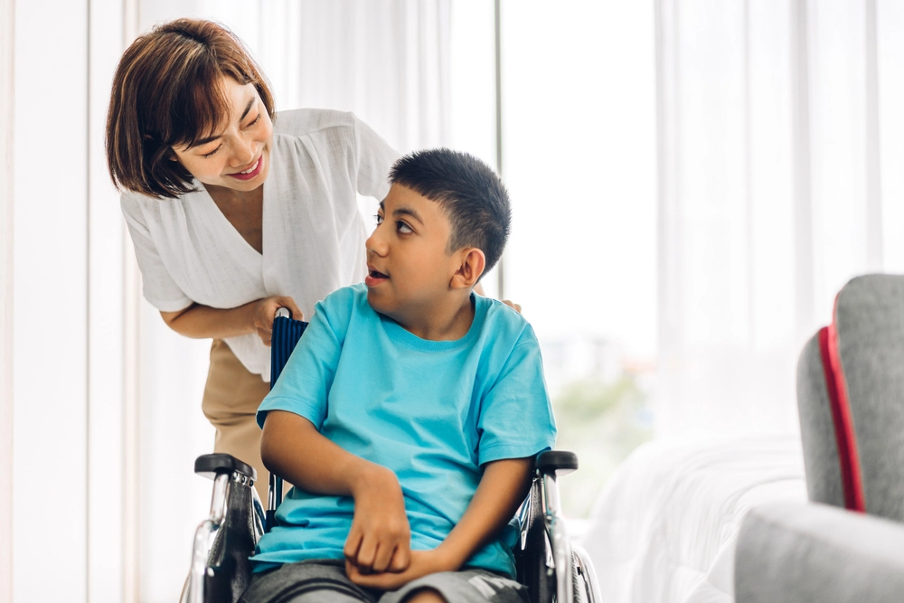 Portrait of enjoy happy love family asian mother playing and carer helping look at disabled son child sitting in wheelchair moments good time at home.disability care